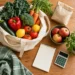 Bolsa reutilizable, alimentos, lista en blanco y calculadora sobre una mesa