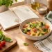 Cuaderno de recetas junto a un plato de pasta con verduras